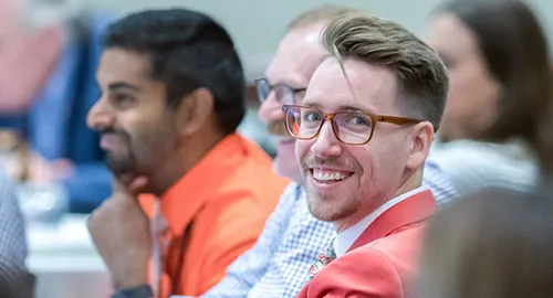 A licensing advisor sitting in a row with other advisors smiles at the camera during an NCARB training event.