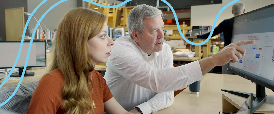 A man and woman working together at a computer, both focused on the screen