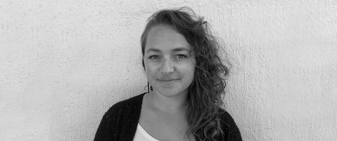 Courtney Zunis: Black and white photo of woman standing in front of concrete wall.