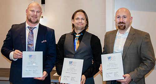 Three IPAL graduates from CityLab-Orlando pose and hold their degrees.