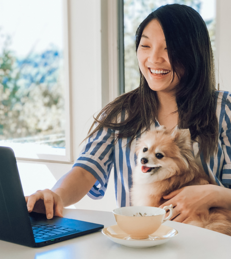 Joann Lui working at a computer with her dog.