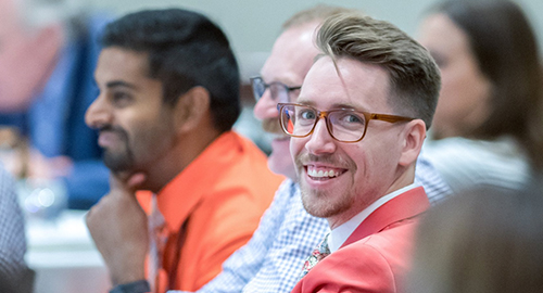 A licensing advisor sitting in a row with other advisors smiles at the camera during an NCARB training event.