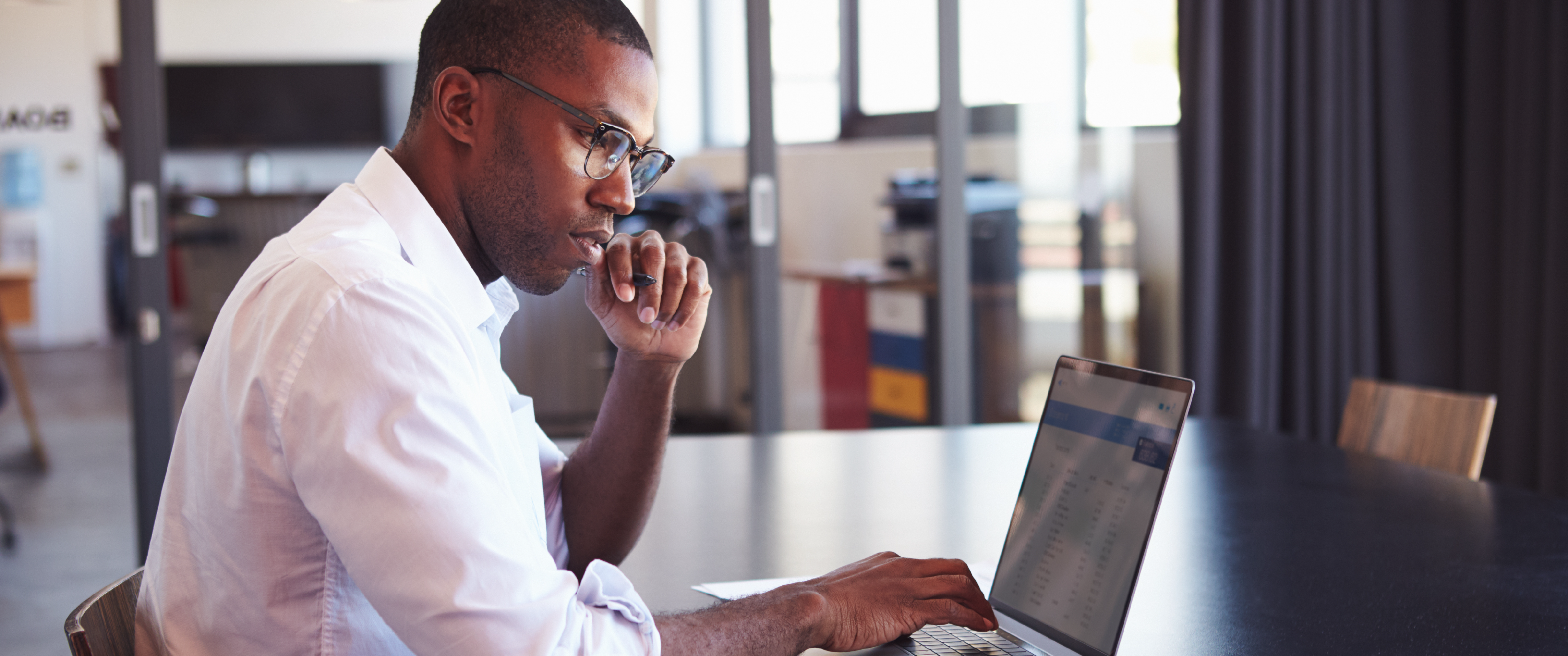 A man of color looking at his laptop. 