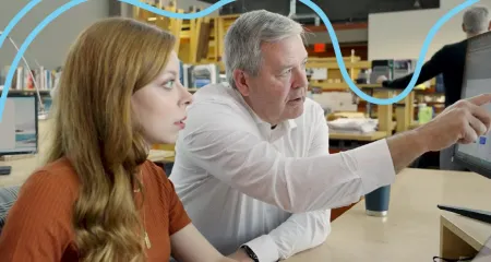 A man and woman working together at a computer, both focused on the screen