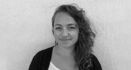 Courtney Zunis: Black and white photo of woman standing in front of concrete wall.