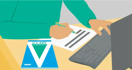 Image of person in a green sweater studying for a test at a desk, with a computer and piece of paper in front of him. Also on the desk is NCARB's "Your Guide to ARE 5.0" brochure. 