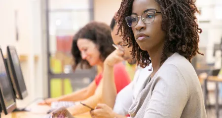 A woman of color looking at a computer. 
