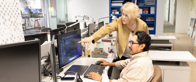A licensing advisor points to a licensure candidate's computer screen in an office.