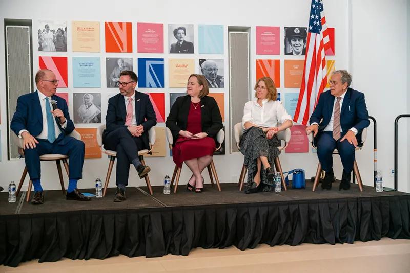 A panel of leaders from NCARB, ARB, and other organizations sit on a stage while answering questions. An American flag and British flag are in the background.