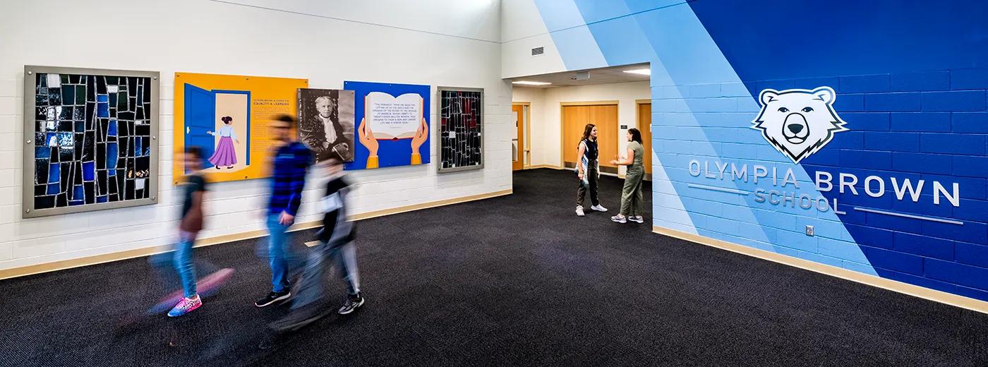 Rendering of the Olympia Brown School entry way, including the name of the school affixed to a wall and students walking by.