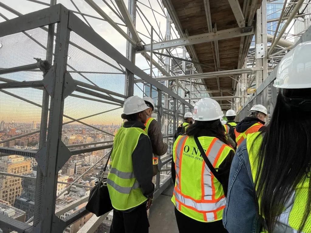 Licensure candidates wearing hard hats visit a construction site.