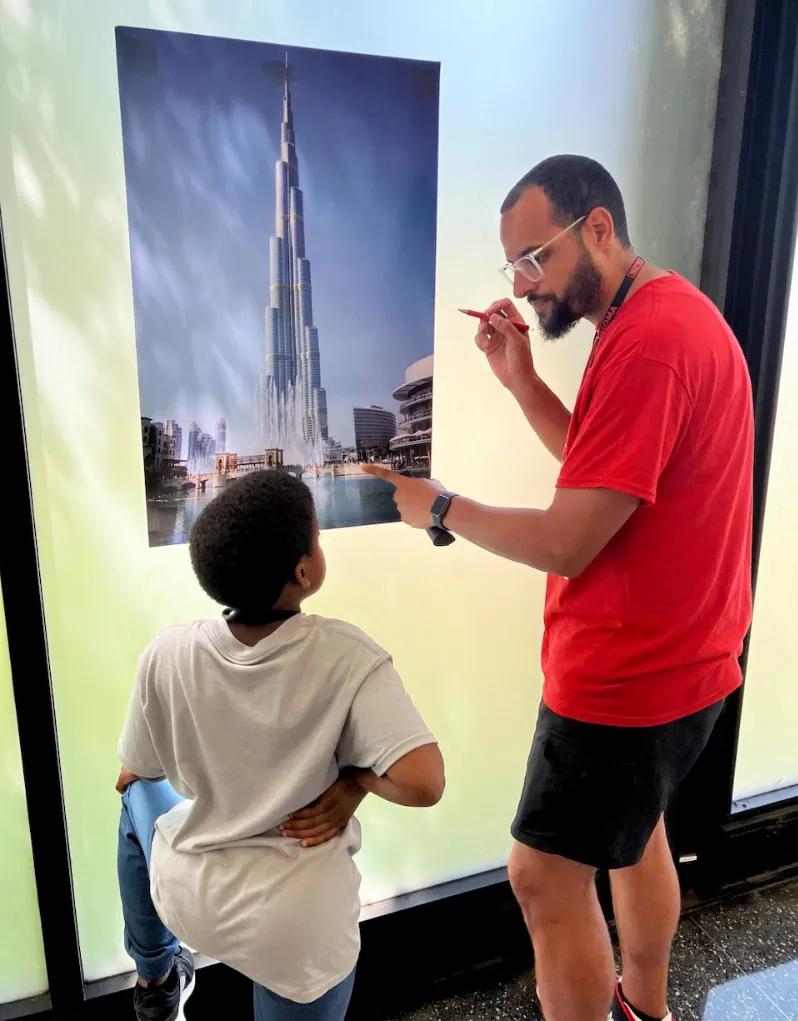 Richie Hands is talking with one of his mentees and pointing to a photo of a building.
